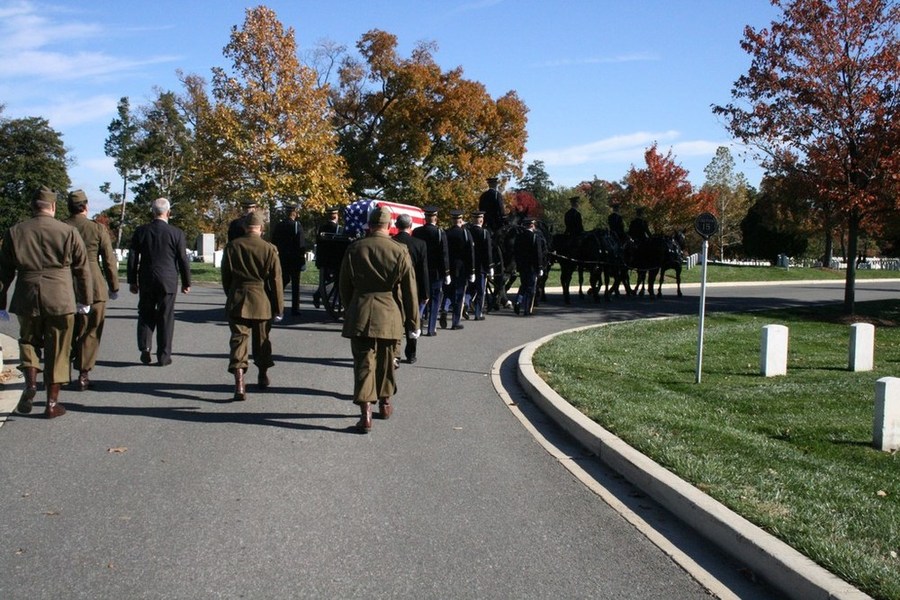 Two honorary pallbearers, in suits, who were Tomb Guards under George's leadership followed by the five Reenacters in WWII Uniforms who wore the 83rd patch